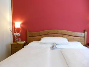 a bedroom with a white bed with a red wall at Hotel Ristorante Daino in Pietramurata