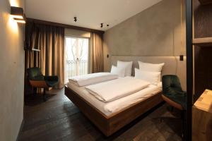 a bedroom with a bed with white sheets and a window at Wailtl Hotel in Dorfen