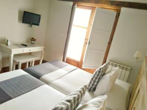 a bedroom with two beds and a desk and a television at Casa Fidela in Lomeña