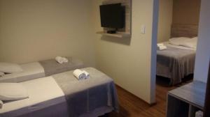 a small room with two beds and a television at Rivero Hotel in Chuí