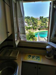 a kitchen with a window with a view of a pool at Magdalini in Votsi