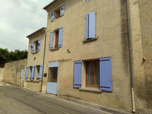 a building with blue shuttered windows on a street at Les Studios proche du Mont Ventoux in Mazan