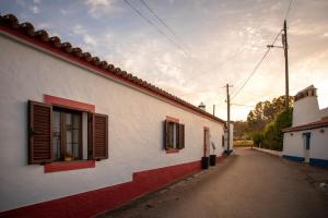 an alley with a white building with red windows at Aleixo's House | Alentejo in Monforte