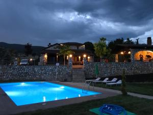 a swimming pool in front of a house at night at Petrines Villes Avramilias in Avramiliá