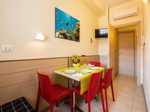 a dining room with a table and red chairs at Appartamenti Lira in Cattolica