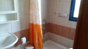 a bathroom with an orange shower curtain next to a sink at Vlachogiannis EL Estate in Skala Rachoniou
