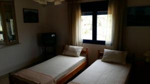 two beds in a room with a window at Vlachogiannis EL Estate in Skala Rachoniou