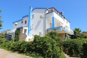 a white and blue building with bushes in front of it at Apartments Blue Sea in Mali Lošinj