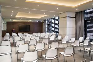 una sala de conferencias con sillas blancas y una pantalla en Pearl Rotana Capital Centre, en Abu Dabi