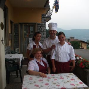 Ein Mann und eine Gruppe von Menschen stehen neben einem Tisch. in der Unterkunft Hotel Poggio d'Oro in Riva di Solto
