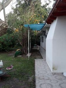 un patio con una sombrilla azul y una casa en Santo Domingo en Esquina