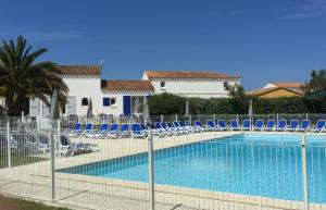 a swimming pool with blue chairs and a fence at Escale à l'île d'Oléron in Le Château-dʼOléron