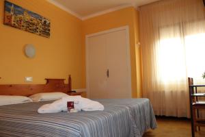a hotel room with two beds and a window at Hostal Fabrellas in Caldes de Malavella