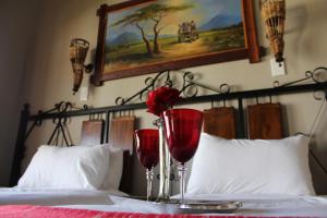 dos copas de vino tinto en una cama en Jarina Guesthouse, en Wolmaranstad