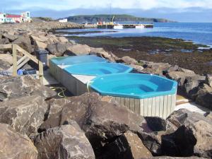 a hot tub on the rocks near the water at Sunna's Guesthouse in Drangsnes