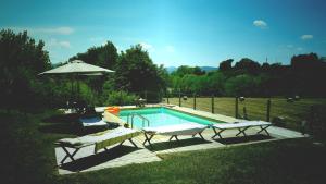 a swimming pool with two chairs and an umbrella at B&B il Fienile di Scarperia in Scarperia