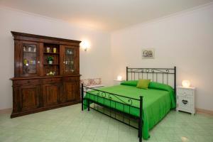 a bedroom with a green bed and a wooden cabinet at Casa Pamela in Capri