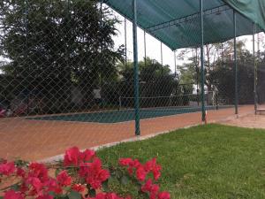a tennis court with a fence and red flowers at Villa Maria Bed and Breakfast in Puerto Escondido