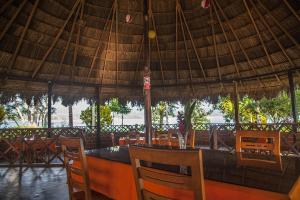 un restaurante con una gran sombrilla de paja, mesas y sillas en Las Jawas Lodge, en Sauce