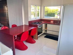 a kitchen with a red table and red chairs at Guarajuba Summer House in Guarajuba