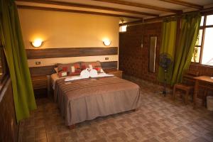 a bedroom with a large bed with green curtains at Las Jawas Lodge in Sauce