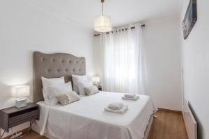 a bedroom with a large white bed with two towels on it at Albufeira Oldtown 330ft Beach Parking AC Wifi in Albufeira