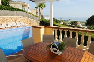 Un patio con mesa y sillas junto a una piscina. en Villa PANORAMA y Villa MIRADOR, en Son Bou