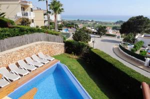una piscina con sillas blancas junto a una calle en Villa PANORAMA y Villa MIRADOR, en Son Bou