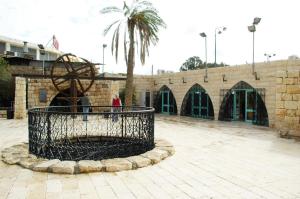 a fountain in front of a building with a palm tree at Old Town Guest House in Beer Sheva