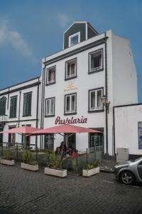 Um edifício branco com um toldo rosa à frente. em Horta Garden em Horta