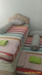a bed with a striped mattress and pillows on it at Apartment Kota Ayodhya - Christine in Tangerang