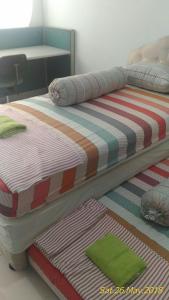 a bed with a striped comforter in a room at Apartment Kota Ayodhya - Christine in Tangerang
