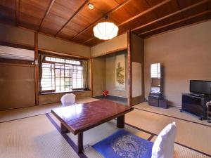 a living room with a table and a tv at Ryokan Inakatei in Kyoto