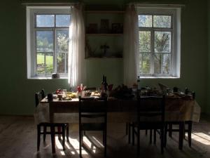 - une salle à manger avec une table, des chaises et 2 fenêtres dans l'établissement Peak Mazeri Guest House, à Mazeri