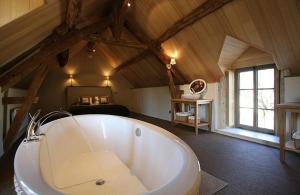 a large white tub in a room with a bedroom at Domaine de la Fouardière in Mulsans