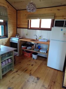 uma cozinha com um frigorífico branco e piso em madeira em UN SUEÑO LOFT em Punta Del Diablo