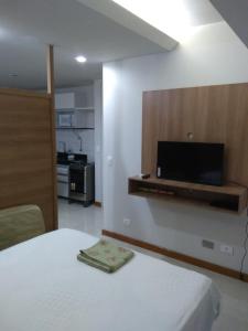 a bedroom with a bed and a flat screen tv at Estúdio Ibiza em Jatiúca in Maceió +27 photos