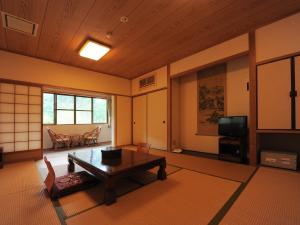 a living room with a table and a tv at Kazuraya in Miyoshi
