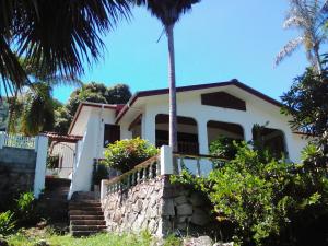 a white house with a palm tree in front of it at Elilia's Haven in Beau Vallon