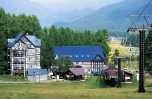 a group of buildings in a field with mountains in the background at Hakuba Sun Valley Hotel in Hakuba