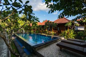 una piscina frente a una casa con un banco en Putra 7 Cottage, en Nusa Lembongan