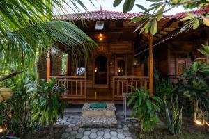 een houten huis met een veranda in een tuin bij Putra 7 Cottage in Nusa Lembongan