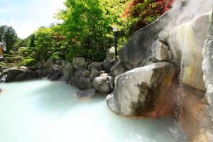 
a waterfall that is surrounded by rocks and trees at Hotel Mahoroba in Noboribetsu
