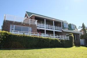 a brick house with a balcony and a hedge at Gill's Beach House in Chintsa