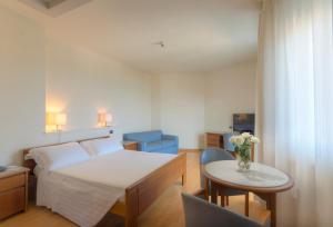 Un dormitorio con una cama y una mesa con un jarrón de flores en Hotel Il Timone, en Porto San Giorgio