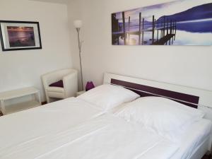 - un lit blanc dans une chambre avec une photo sur le mur dans l'établissement Ferienwohnungen am kleinen See, à Bergen auf Rügen