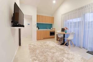 a living room with a table and a tv and a kitchen at Halfmoon Bay Apartment in Auckland