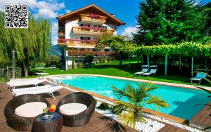 a resort with a swimming pool with chairs and a building at Residence *** Geringerhof in Schenna