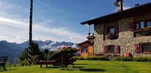 a building with a bench in the grass next to a house at Baita Zeni Tirolerhof in Fiera di Primiero