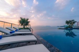 a pool with chairs and the ocean in the background at Boton Blue Hotel & Spa in Nha Trang